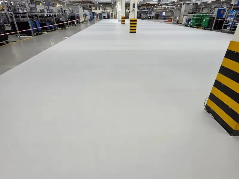 Hellgrauer Boden in einer Produktionshalle mit gelb-schwarz markierten Stützen